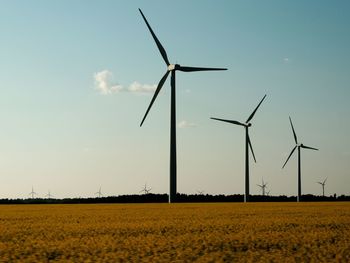 Windmills on landscape against sky