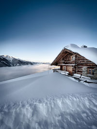 House on snowcapped mountain against sky