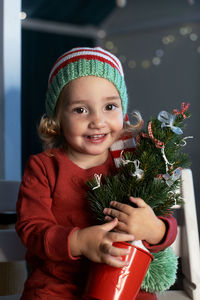 Portrait of young woman holding christmas tree