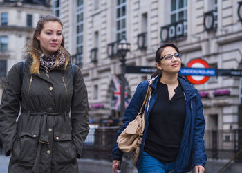 Smiling female friends looking away while walking in city