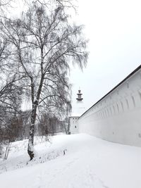 Snow covered trees by building against sky