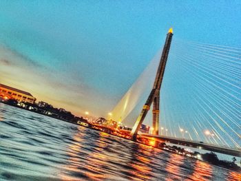 Low angle view of illuminated suspension bridge against sky