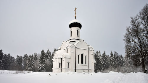 Church by building against clear sky during winter