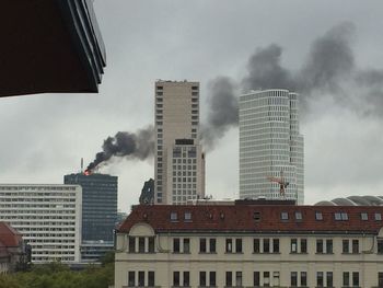 Low angle view of skyscrapers against cloudy sky