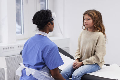 Female doctor talking to girl patient during appointment