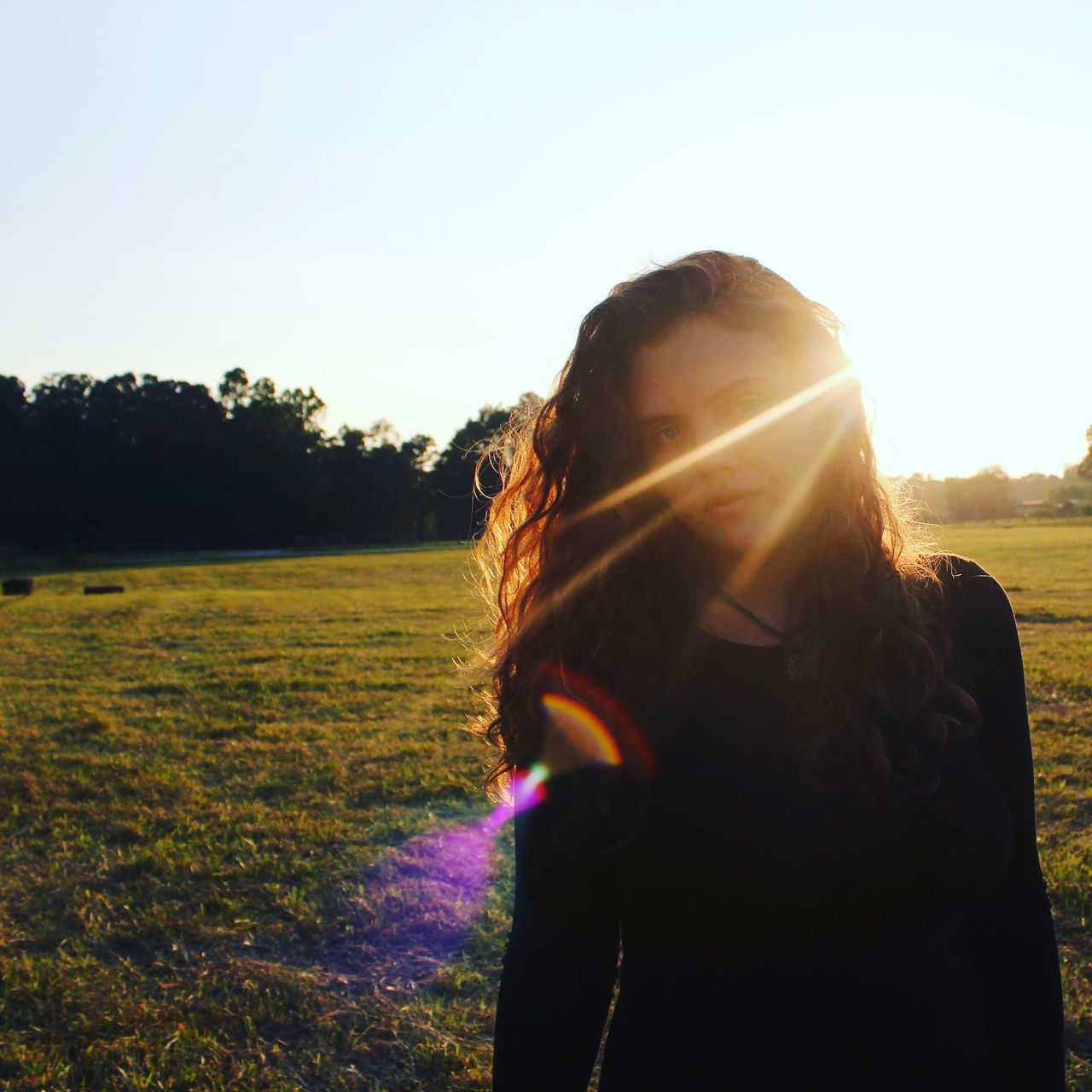 WOMAN STANDING ON FIELD AGAINST BRIGHT SKY