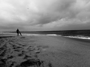 Man walking on beach against sky