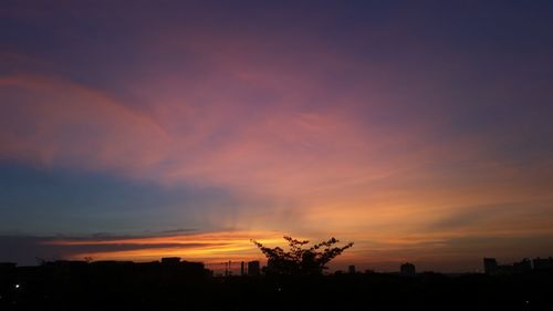 Silhouette city against sky at sunset