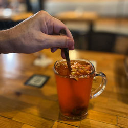 Close-up of hand holding drink on table