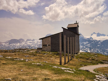 House on field by mountain against sky