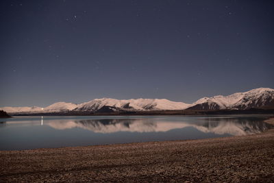 Scenic view of lake and mountains against sky at night