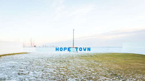 Information sign on snow covered land against sky