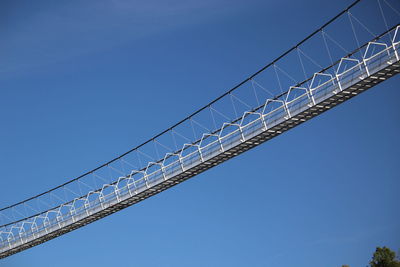 Low angle view of cranes against clear blue sky