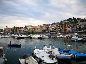 Boats moored in harbor against buildings in city