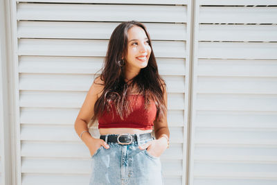 Young woman standing against wall