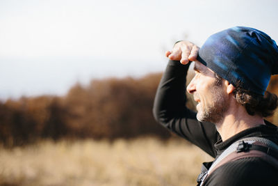 Portrait of man looking away on field against sky