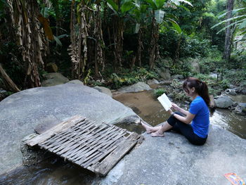 Side view of woman sitting in forest