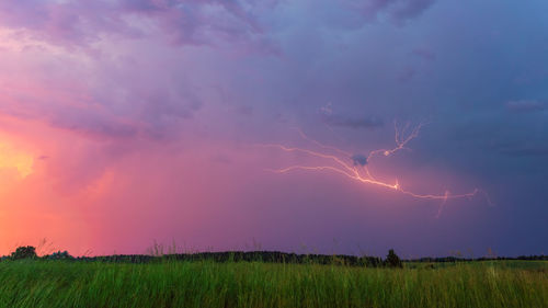 Panoramic view of lightning over field against sky during sunset