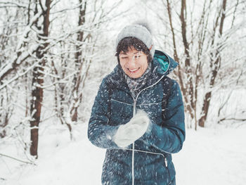 Smiling woman is playing with snow. fun in snowy winter forest. woman laughs and walks through wood.