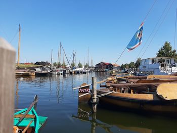 Boats moored at harbor against clear sky