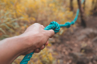 Close-up of hand holding blue rope