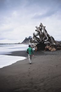 Man walking at beach against sky