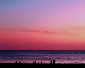 Silhouette people on beach against sky during sunset