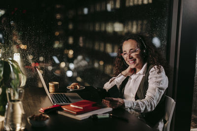 Portrait of smiling young woman using phone in restaurant