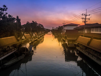 Canal amidst buildings against sky during sunset
