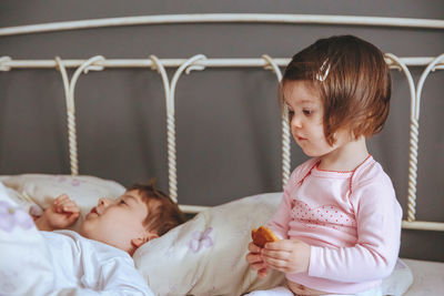 Cheerful mother playing with son and daughter while lying on bed at home