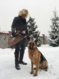 Man with dog standing on snow