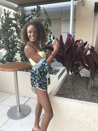 Portrait of smiling young woman standing against tree