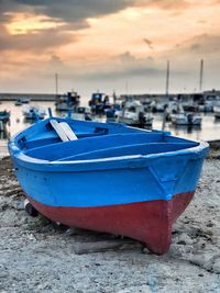 Boat moored on beach against sky during sunset