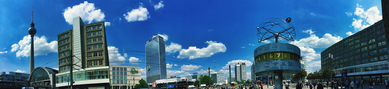 building exterior, architecture, built structure, sky, city, blue, cloud - sky, low angle view, cloud, city life, building, day, tower, street light, modern, sunlight, panoramic, large group of people, incidental people