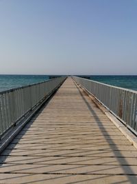 Wooden pier over sea against clear sky