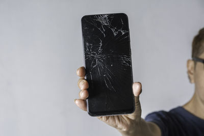 Close-up of hand holding smart phone against white background