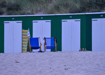 Chairs on beach against blue sky