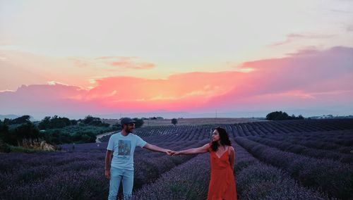 People standing on field against sky during sunset