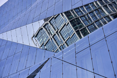 Low angle view of modern glass building against blue sky