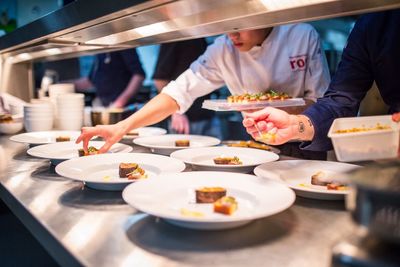 Midsection of chefs serving foods in restaurant