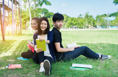 Portrait of smiling young woman sitting on book