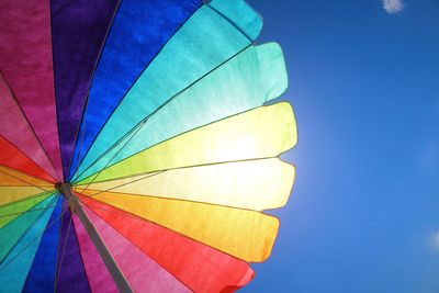 Low angle view of colorful parasol against blue sky