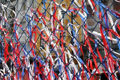 Full frame shot of ribbons tied on chainlink fence in city