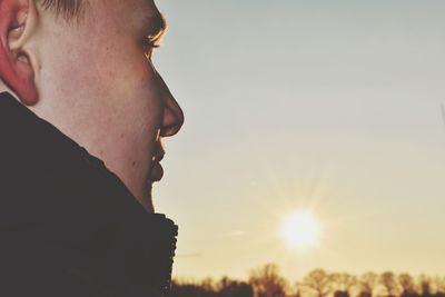 Portrait of young man looking away against sky during sunset