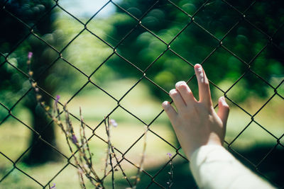 Midsection of person seen through chainlink fence