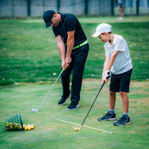 Full length of friends playing with golf course