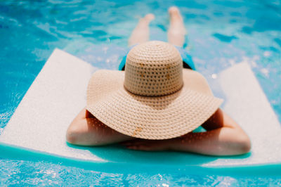 Person wearing hat relaxing in swimming pool