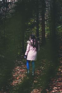 Woman standing by tree in forest
