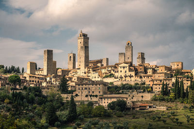 Medieval buildings in tuscan city against cloudy sky, san gimignano, italy