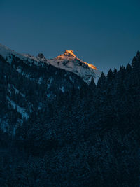 Low angle view of snowcapped mountains against clear sky